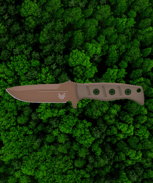 A knife is laying on the ground in the grass.