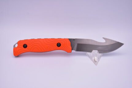 A knife with an orange handle on top of a white surface.