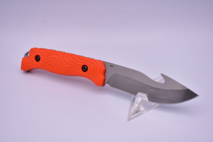 A knife with an orange handle on top of a stand.